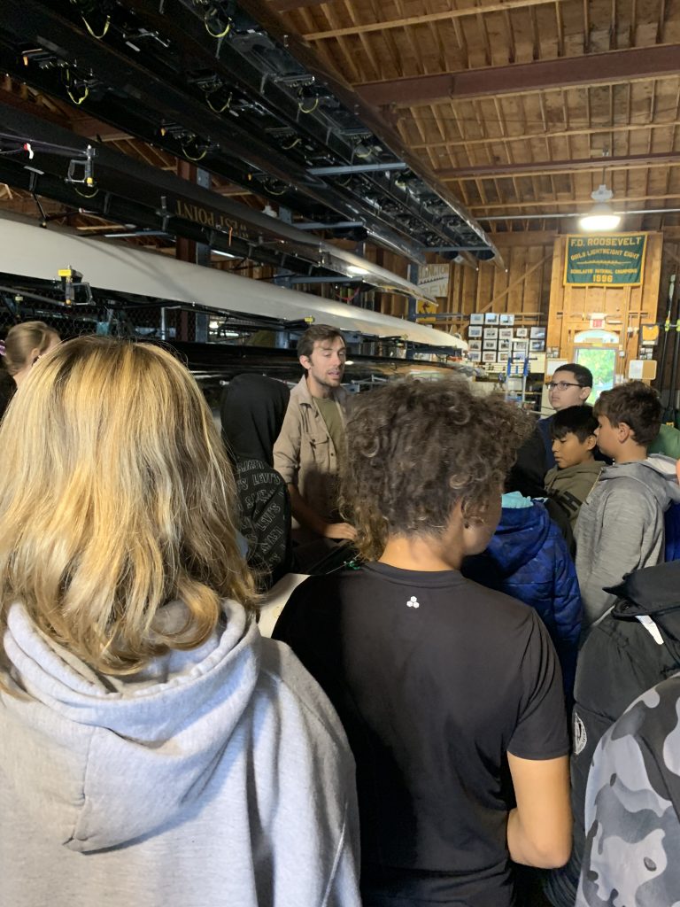 Coach Andrew Runne showed them the parts of a crew shell, explaining the difference between equipment then versus now.